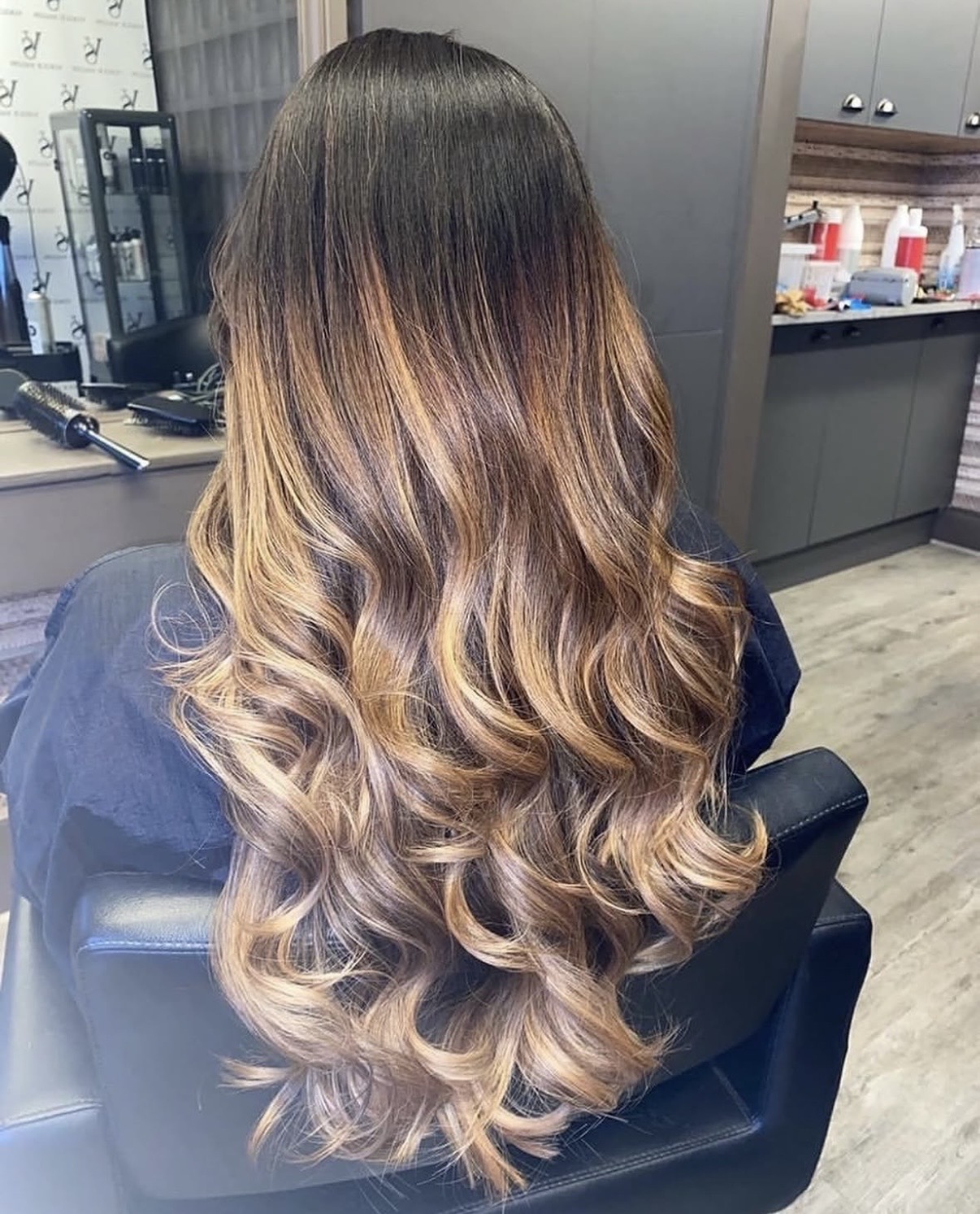 Long glossy brunette balayage styled in soft waves at Vogue Salon